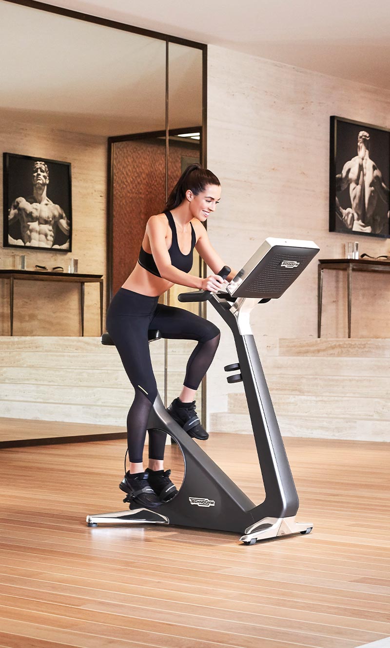 Young woman pedaling on Bike Personal designer exercise bike in a luxury home setting